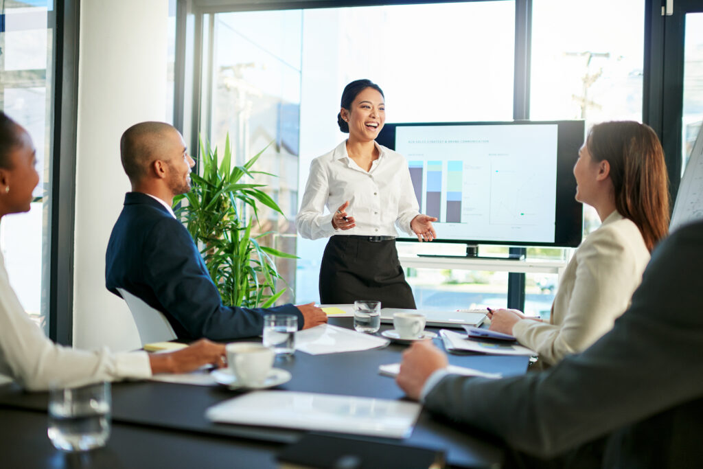 A business professional giving a presentation to her clients in the boardroom.