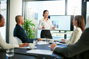 A business professional giving a presentation to her clients in the boardroom.