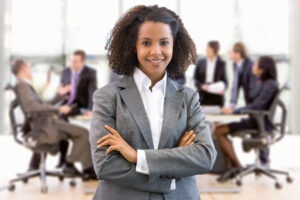 A young business professional standing confidently with her team in the background.