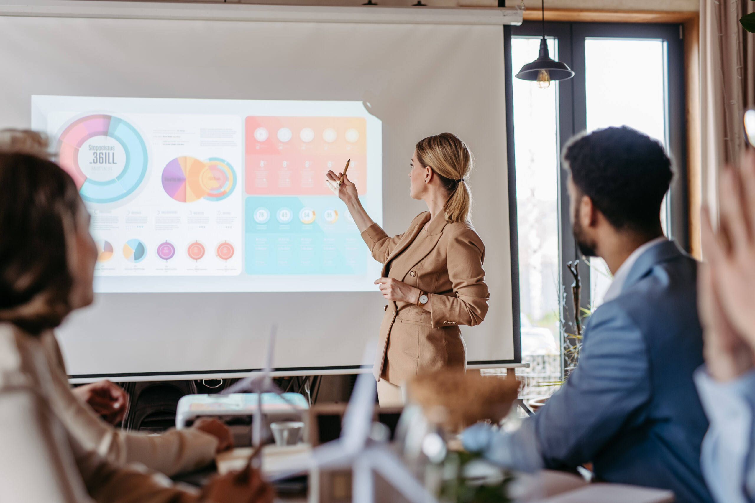 A business professional presenting pie charts and graphs on a large screen.