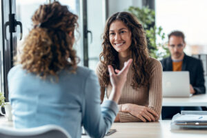A smiling young woman engaged in a discussion in a modern office setting