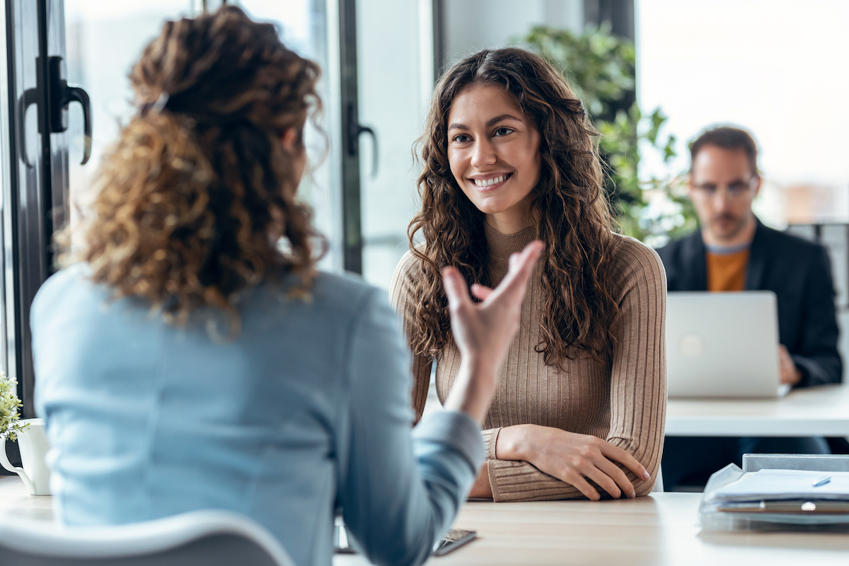 A smiling young woman engaged in a discussion in a modern office setting